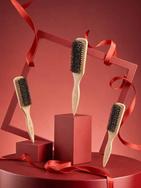 Three Ruby Vibe Co wooden bristle hairbrushes displayed on red geometric blocks with a ribbon.